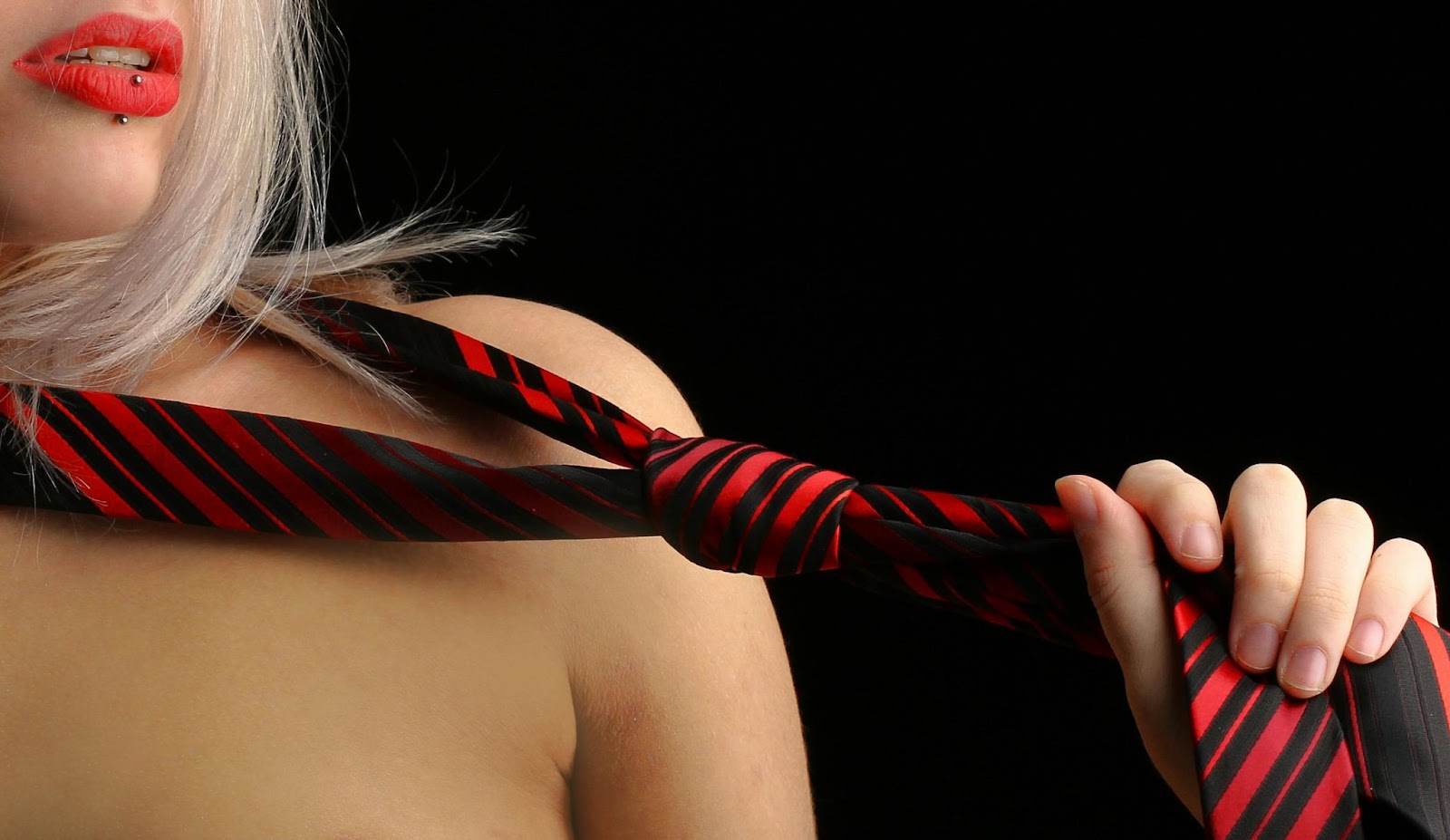 Woman with red lipstick pulling a red and black tie
