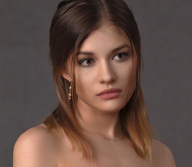 Young woman with straight brown hair wearing gold earrings and a necklace